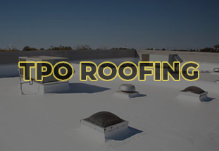 A wide-angle photo of a commercial building with a flat TPO roofing system, featuring white thermoplastic membrane sheets and seams.