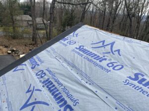 A photo of Storm Proof's team installing Summit 60 synthetic underlayment on a roof.